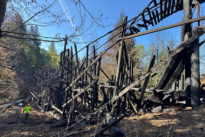Charred timber and hanging rail are all that remain of the bridge.  Charred timber and hanging rail are all that remain of the bridge.