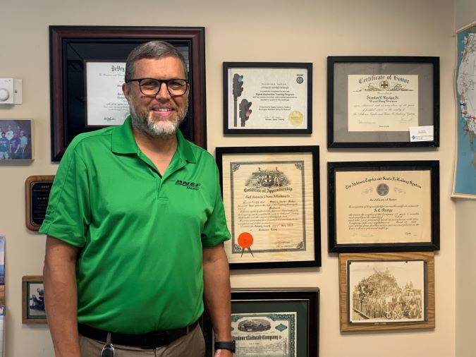 Shane Mudge next to a wall of his family’s railroading awards and achievements.  Shane Mudge next to a wall of his family’s railroading awards and achievements.