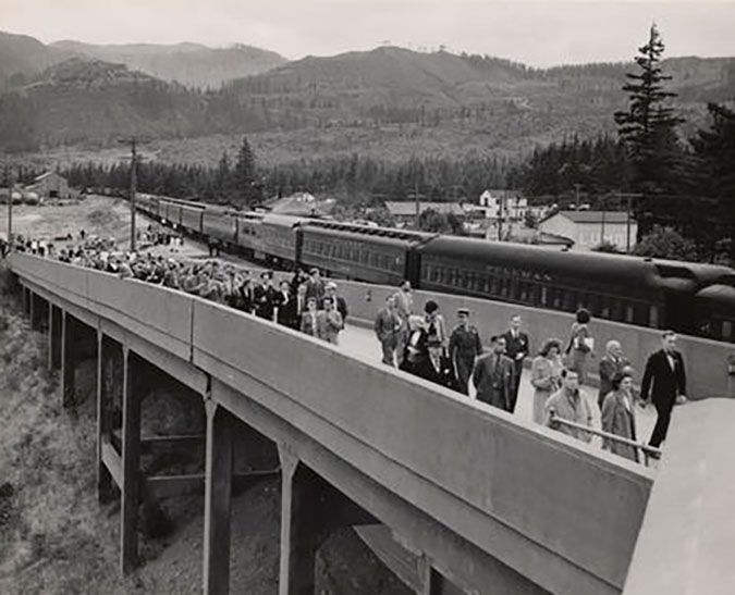 A crowd of people walking up a ramp next to an SP&S train at North Bonneville Station on June 29, 1945  A crowd of people walking up a ramp next to an SP&S train at North Bonneville Station on June 29, 1945