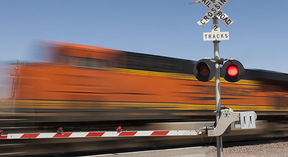 A BNSF train travels at high speed through a grade crossing. A BNSF train travels at high speed through a grade crossing.